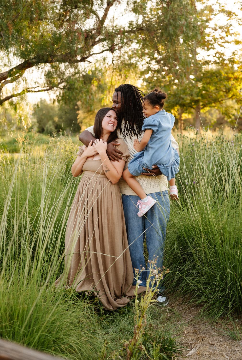 A family embracing in a meadow at golden hour