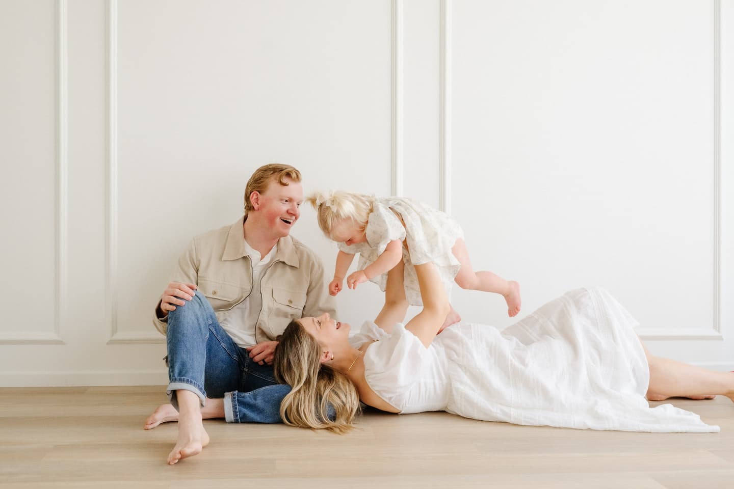 A family together at the studio, mother lifting her daughter into the air
